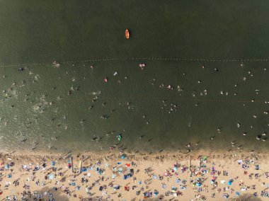 Summer Lake Sahili 'nin hava aracı görüntüsü. Yeşil gölde güneşli bir yaz tatili. Güneşlenmek ve sahilde dinlenmek. Polonya 'daki gölde tatil. İnsanlar göl sahilinde güneşleniyor..