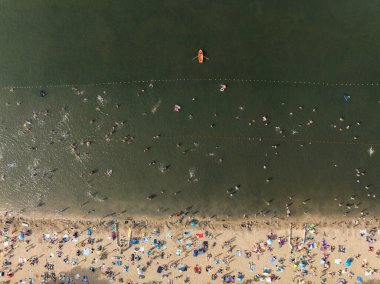 Summer Lake Sahili 'nin hava aracı görüntüsü. Yeşil gölde güneşli bir yaz tatili. Güneşlenmek ve sahilde dinlenmek. Polonya 'daki gölde tatil. İnsanlar göl sahilinde güneşleniyor..