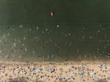 Summer Lake Sahili 'nin hava aracı görüntüsü. Yeşil gölde güneşli bir yaz tatili. Güneşlenmek ve sahilde dinlenmek. Polonya 'daki gölde tatil. İnsanlar göl sahilinde güneşleniyor..