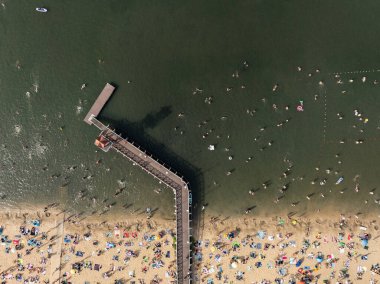 Summer Lake Sahili 'nin hava aracı görüntüsü. Yeşil gölde güneşli bir yaz tatili. Güneşlenmek ve sahilde dinlenmek. Polonya 'daki gölde tatil. İnsanlar göl sahilinde güneşleniyor..