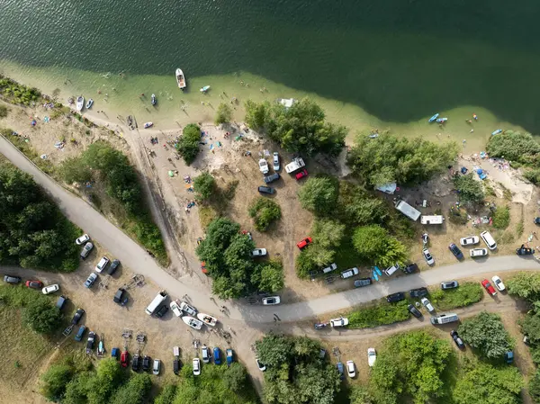 Summer Lake Sahili 'nin hava aracı görüntüsü. Yeşil gölde güneşli bir yaz tatili. Güneşlenmek ve sahilde dinlenmek. Polonya 'daki gölde tatil. İnsanlar göl sahilinde güneşleniyor..