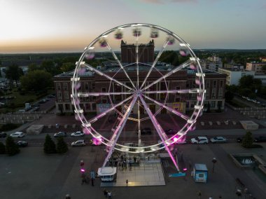 Colorful Ferris wheel From a bird's eye view drone at night. Large colorful Ferris wheel in city center. Aerial drone view on Colorful Ferris wheel spinning in the city center Dabrowa Gornicza Poland clipart