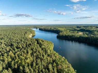 Yeşil ormanlarla çevrili bir gölde kayak yapan insanların insansız hava aracı görüntüsü. Masurian Gölü Bölgesi 'nde kırmızı kanolarla geziyorlar. Kulka Reserve 'deki Lesk Gölü, Poland.Kulka Reserve, Masuria, Polonya.