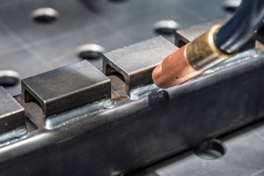 Robot çeliği kaynak yapar. Kaynak kafa. Kaynak robotu. CNC kaynaklama. Kaynak işleminin robotlaştırılması ve otomasyonu. Robot kaynak çeliği. Endüstriyel kaynak robotu ve metal parçalarıyla çalışıyor.