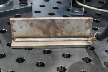 Robot çeliği kaynak yapar. Kaynak kafa. Kaynak robotu. CNC kaynaklama. Kaynak işleminin robotlaştırılması ve otomasyonu. Robot kaynak çeliği. Endüstriyel kaynak robotu ve metal parçalarıyla çalışıyor.