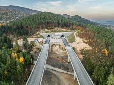 Construction of a highway with viaducts and tunnels baskid mountains.Aerial drone view of unfinished highway construction site in mountains in autumn. Construction of expressway in beskid mountains. clipart