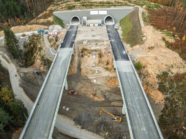 Viyadük ve tünelleri olan bir otoyol inşaatı Baskid dağları. Sonbaharda dağlarda tamamlanmamış otoyol inşaatının insansız hava aracı görüntüsü. Beskid dağlarında otoyol inşaatı.