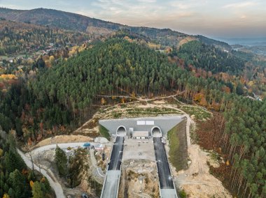 Viyadük ve tünelleri olan bir otoyol inşaatı Baskid dağları. Sonbaharda dağlarda tamamlanmamış otoyol inşaatının insansız hava aracı görüntüsü. Beskid dağlarında otoyol inşaatı.