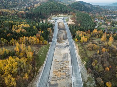 Viyadük ve tünelleri olan bir otoyol inşaatı Baskid dağları. Sonbaharda dağlarda tamamlanmamış otoyol inşaatının insansız hava aracı görüntüsü. Beskid dağlarında otoyol inşaatı.