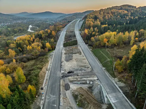 Viyadük ve tünelleri olan bir otoyol inşaatı Baskid dağları. Sonbaharda dağlarda tamamlanmamış otoyol inşaatının insansız hava aracı görüntüsü. Beskid dağlarında otoyol inşaatı.