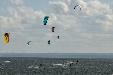 İnsanlar denizde uçurtma sörfü ya da uçurtma sörfü yapıyor. Yaz sporu uçurtma uçurmayı öğreniyor. Körfezde uçurtma sörfü dersleri. Kite sörfü. Hel Yarımadası, Puck Körfezi, Jastarnia, Polonya.