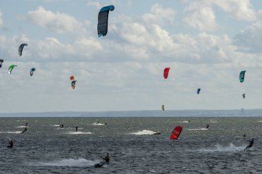 İnsanlar denizde uçurtma sörfü ya da uçurtma sörfü yapıyor. Yaz sporu uçurtma uçurmayı öğreniyor. Körfezde uçurtma sörfü dersleri. Kite sörfü. Hel Yarımadası, Puck Körfezi, Jastarnia, Polonya.