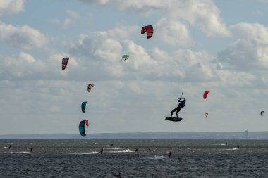 People swim on the sea on a kiteboard or kitesurfing. Summer sport learning how to kitesurf. Kitesurfing lessons on the bay.Kite surfing on bay. Hel Peninsula,Puck bay, Jastarnia, Poland. clipart