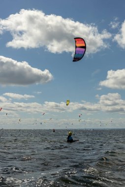 İnsanlar denizde uçurtma sörfü ya da uçurtma sörfü yapıyor. Yaz sporu uçurtma uçurmayı öğreniyor. Körfezde uçurtma sörfü dersleri. Kite sörfü. Hel Yarımadası, Puck Körfezi, Jastarnia, Polonya.