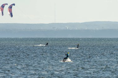 People swim on the sea on a kiteboard or kitesurfing. Summer sport learning how to kitesurf. Kitesurfing lessons on the bay.Kite surfing on bay. Hel Peninsula,Puck bay, Jastarnia, Poland. clipart