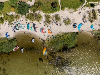 İnsanlar denizde uçurtma sörfü ya da uçurtma sörfü yapıyor. Yaz sporu uçurtma uçurmayı öğreniyor. Körfezde uçurtma sörfü dersleri. Kite sörfü. Hel Yarımadası, Puck Körfezi, Jastarnia, Polonya.