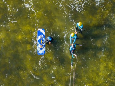 İnsanlar denizde uçurtma sörfü ya da uçurtma sörfü yapıyor. Yaz sporu uçurtma uçurmayı öğreniyor. Körfezde uçurtma sörfü dersleri. Kite sörfü. Hel Yarımadası, Puck Körfezi, Jastarnia, Polonya.