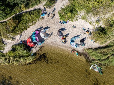 İnsanlar denizde uçurtma sörfü ya da uçurtma sörfü yapıyor. Yaz sporu uçurtma uçurmayı öğreniyor. Körfezde uçurtma sörfü dersleri. Kite sörfü. Hel Yarımadası, Puck Körfezi, Jastarnia, Polonya.