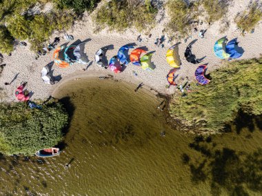 İnsanlar denizde uçurtma sörfü ya da uçurtma sörfü yapıyor. Yaz sporu uçurtma uçurmayı öğreniyor. Körfezde uçurtma sörfü dersleri. Kite sörfü. Hel Yarımadası, Puck Körfezi, Jastarnia, Polonya.