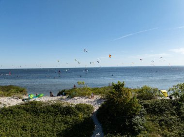 İnsanlar denizde uçurtma sörfü ya da uçurtma sörfü yapıyor. Yaz sporu uçurtma uçurmayı öğreniyor. Körfezde uçurtma sörfü dersleri. Kite sörfü. Hel Yarımadası, Puck Körfezi, Jastarnia, Polonya.