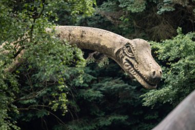 Parktaki bir dinozor heykelinin yakın plan görüntüsü detaylı tasarımı, canlı renkleri ve canlı görünüşü, yaratıcılığı paleontolojik doğrulukla harmanlıyor..