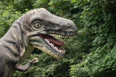 Parktaki bir dinozor heykelinin yakın plan görüntüsü detaylı tasarımı, canlı renkleri ve canlı görünüşü, yaratıcılığı paleontolojik doğrulukla harmanlıyor..