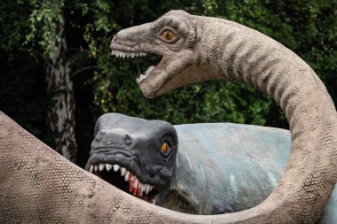 Parktaki bir dinozor heykelinin yakın plan görüntüsü detaylı tasarımı, canlı renkleri ve canlı görünüşü, yaratıcılığı paleontolojik doğrulukla harmanlıyor..