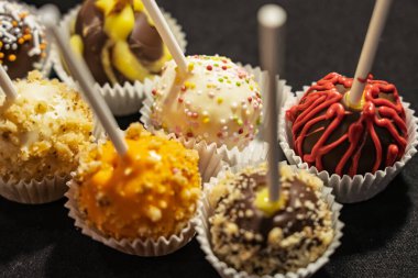 Dekoratif çikolata çubukların üzerinde canlı renkler ve malzemeler sergilenerek sergilenir. Çikolata parçacıklı renkli lolipoplar ve diğer tatlı malzemeler.