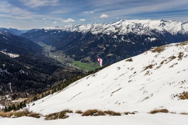 Paraglider karlı bir dağ sırasının üzerindeki bulutlarda süzülüyor. Dolomitler 'deki bir vadide bulutların üzerinde paraglider, Alpler. Paraglider dağlarda karlı bir yamaçtan kalkıyor. Pinzolo, İtalya.