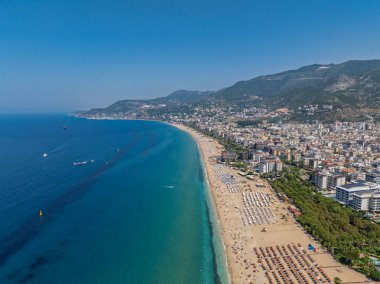 Alanya, Türkiye 'deki Kleopatra Sahili' nin insansız hava aracı görüntüsü. Alanya turkuvaz denizi, kumlu plaj, uçurumlar, mağaralı tepeler ve yukarıdan güneşli yaz günü kıyı şeridi. Yaz Akdeniz