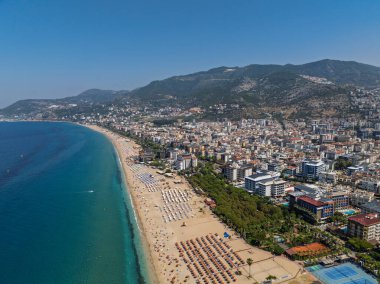 Alanya, Türkiye 'deki Kleopatra Sahili' nin insansız hava aracı görüntüsü. Alanya turkuvaz denizi, kumlu plaj, uçurumlar, mağaralı tepeler ve yukarıdan güneşli yaz günü kıyı şeridi. Yaz Akdeniz