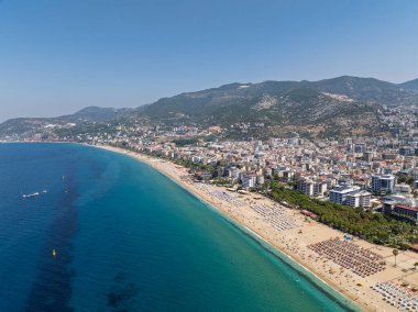 Alanya, Türkiye 'deki Kleopatra Sahili' nin insansız hava aracı görüntüsü. Alanya turkuvaz denizi, kumlu plaj, uçurumlar, mağaralı tepeler ve yukarıdan güneşli yaz günü kıyı şeridi. Yaz Akdeniz