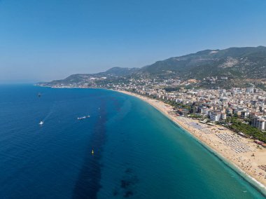 Alanya, Türkiye 'deki Kleopatra Sahili' nin insansız hava aracı görüntüsü. Alanya turkuvaz denizi, kumlu plaj, uçurumlar, mağaralı tepeler ve yukarıdan güneşli yaz günü kıyı şeridi. Yaz Akdeniz