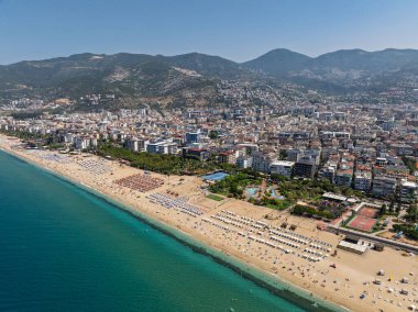 Alanya, Türkiye 'deki Kleopatra Sahili' nin insansız hava aracı görüntüsü. Alanya turkuvaz denizi, kumlu plaj, uçurumlar, mağaralı tepeler ve yukarıdan güneşli yaz günü kıyı şeridi. Yaz Akdeniz