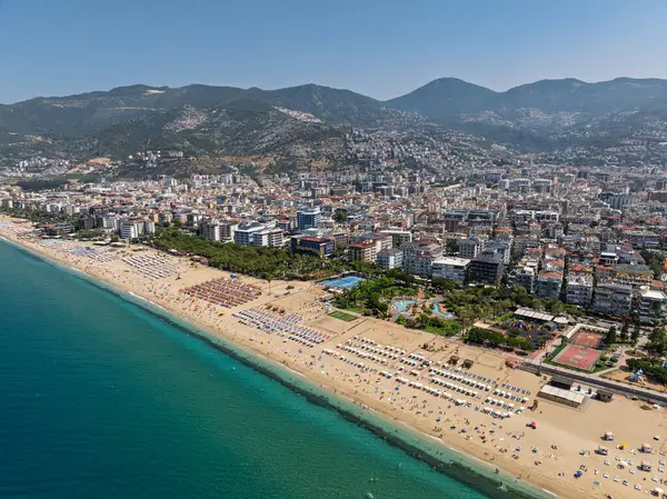 Alanya, Türkiye 'deki Kleopatra Sahili' nin insansız hava aracı görüntüsü. Alanya turkuvaz denizi, kumlu plaj, uçurumlar, mağaralı tepeler ve yukarıdan güneşli yaz günü kıyı şeridi. Yaz Akdeniz