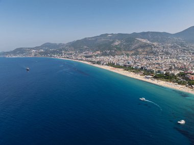 Alanya, Türkiye 'deki Kleopatra Sahili' nin insansız hava aracı görüntüsü. Alanya turkuvaz denizi, kumlu plaj, uçurumlar, mağaralı tepeler ve yukarıdan güneşli yaz günü kıyı şeridi. Yaz Akdeniz
