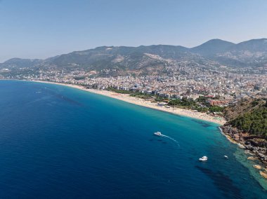 Alanya, Türkiye 'deki Kleopatra Sahili' nin insansız hava aracı görüntüsü. Alanya turkuvaz denizi, kumlu plaj, uçurumlar, mağaralı tepeler ve yukarıdan güneşli yaz günü kıyı şeridi. Yaz Akdeniz