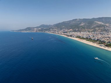 Alanya, Türkiye 'deki Kleopatra Sahili' nin insansız hava aracı görüntüsü. Alanya turkuvaz denizi, kumlu plaj, uçurumlar, mağaralı tepeler ve yukarıdan güneşli yaz günü kıyı şeridi. Yaz Akdeniz
