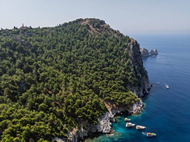 Türkiye 'nin Alanya kentindeki kayalık kıyı ve orman yakınlarındaki teknelerle turkuaz deniz manzarası. Akdeniz kıyı şeridinin ve temiz suyun insansız hava aracı görüntüleri. Alanya 'da yaz tatili