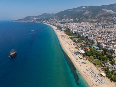 Alanya, Türkiye 'deki Kleopatra Sahili' nin insansız hava aracı görüntüsü. Alanya turkuvaz denizi, kumlu plaj, uçurumlar, mağaralı tepeler ve yukarıdan güneşli yaz günü kıyı şeridi. Yaz Akdeniz