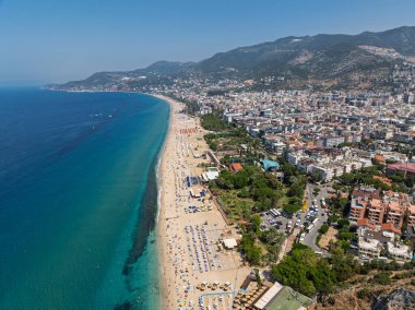 Alanya, Türkiye 'deki Kleopatra Sahili' nin insansız hava aracı görüntüsü. Alanya turkuvaz denizi, kumlu plaj, uçurumlar, mağaralı tepeler ve yukarıdan güneşli yaz günü kıyı şeridi. Yaz Akdeniz