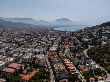 Türkiye 'deki Alanya şehrinin havadan görüntüsü. Yoğun kentsel binalar, Akdeniz kıyı şeridi, yeşil tepeler ve dağlar, açık yaz günlerinde insansız hava araçlarından. Alanya şehrindeki binaların ve otellerin havadan görüntüsü.