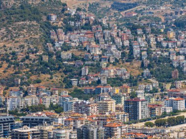 Türkiye 'deki Alanya şehrinin havadan görüntüsü. Yoğun kentsel binalar, Akdeniz kıyı şeridi, yeşil tepeler ve dağlar, açık yaz günlerinde insansız hava araçlarından. Alanya şehrindeki binaların ve otellerin havadan görüntüsü.
