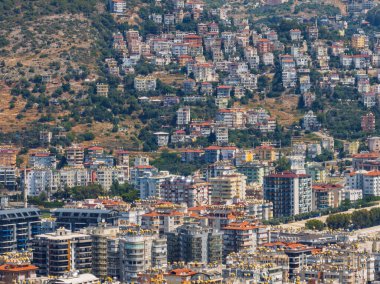 Türkiye 'deki Alanya şehrinin havadan görüntüsü. Yoğun kentsel binalar, Akdeniz kıyı şeridi, yeşil tepeler ve dağlar, açık yaz günlerinde insansız hava araçlarından. Alanya şehrindeki binaların ve otellerin havadan görüntüsü.