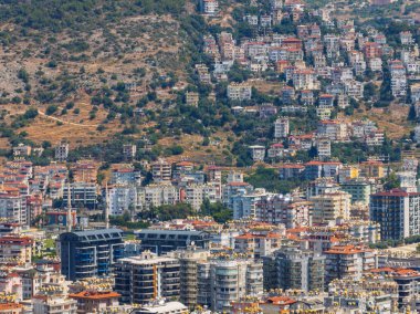 Türkiye 'deki Alanya şehrinin havadan görüntüsü. Yoğun kentsel binalar, Akdeniz kıyı şeridi, yeşil tepeler ve dağlar, açık yaz günlerinde insansız hava araçlarından. Alanya şehrindeki binaların ve otellerin havadan görüntüsü.