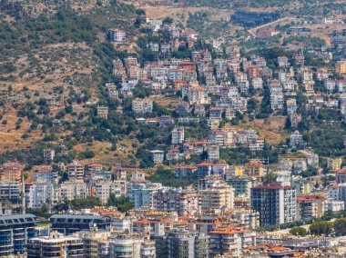 Türkiye 'deki Alanya şehrinin havadan görüntüsü. Yoğun kentsel binalar, Akdeniz kıyı şeridi, yeşil tepeler ve dağlar, açık yaz günlerinde insansız hava araçlarından. Alanya şehrindeki binaların ve otellerin havadan görüntüsü.