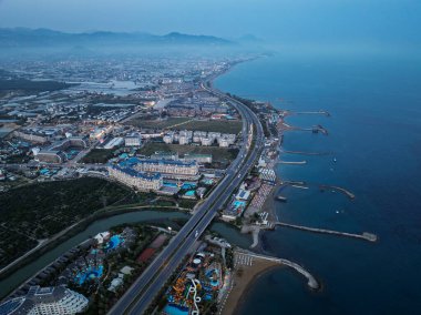 Türkiye 'nin Alanya kentindeki Türkler üzerinde gece karanlığına muhteşem hava günbatımı. Alanya kıyı şeridi, tatil beldeleri, marina, oteller ve Akdeniz insansız hava aracı manzaralı şehir ışıkları. Akdeniz kıyı şeridi