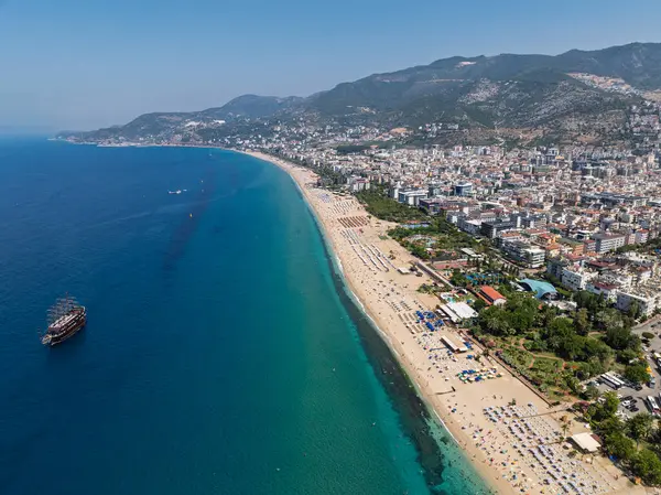 Alanya, Türkiye 'deki Kleopatra Sahili' nin insansız hava aracı görüntüsü. Alanya turkuvaz denizi, kumlu plaj, uçurumlar, mağaralı tepeler ve yukarıdan güneşli yaz günü kıyı şeridi. Yaz Akdeniz