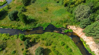 Bereketli yeşil çayırlar ve yaz doğa manzarasıyla çevrili Liswarta Nehri boyunca yüzen renkli kanoların hava aracı görüntüsü. Polonya 'da nehirde kayak yaparken. Nehirdeki kanolar.