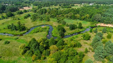 Bereketli yeşil çayırlar ve yaz doğa manzarasıyla çevrili Liswarta Nehri boyunca yüzen renkli kanoların hava aracı görüntüsü. Polonya 'da nehirde kayak yaparken. Nehirdeki kanolar.